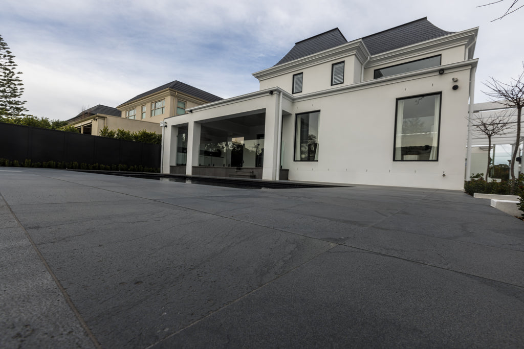 Sealed bluestone pavers at prestige Melbourne property showing wide low-angle view of dark surface and premium residence