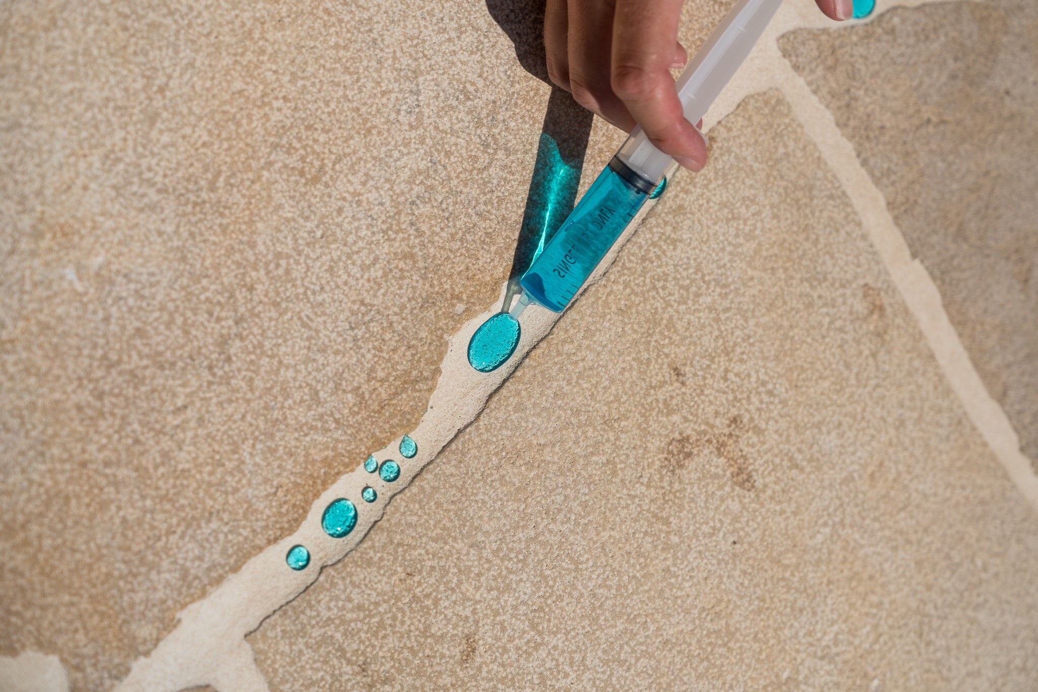 Blue water beading on sealed grout lines — demonstrating water repellency after sealing